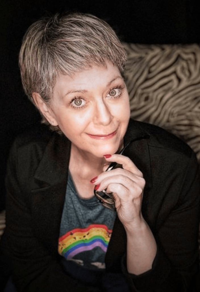 1updated_tq_com_hero_photo - Tracy Quinlan Image of Edmonton Astrologer Tracy Quinlan sitting forward in a Zebra striped chair
