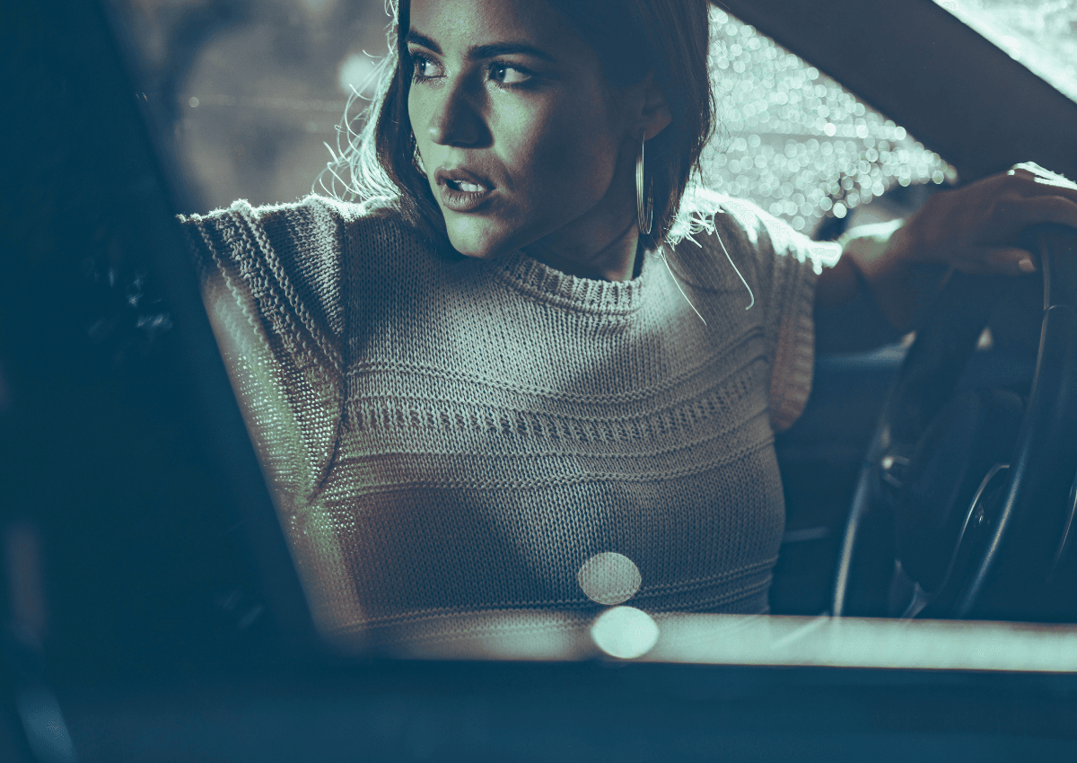 Reversing - Tracy Quinlan For SEO and accessibility, describe what's actually in the image first, not the metaphor. I'd use: Alt text: Woman looking over her shoulder from the driver's seat of a car, symbolizing reflection, review, and changing direction during Mercury retrograde.
